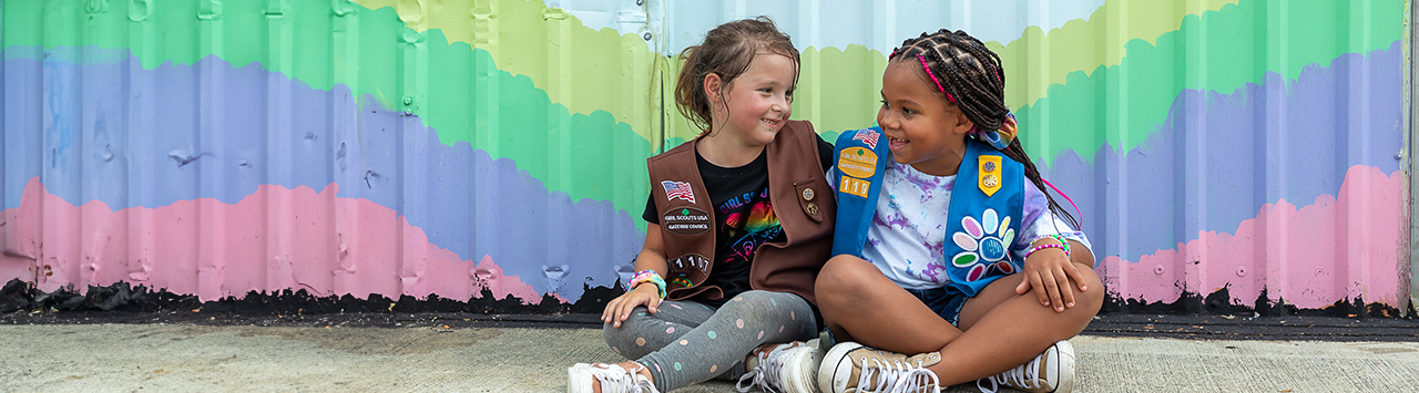  Daisy and Brownie Girl Scout sitting down smiling at each other. 
