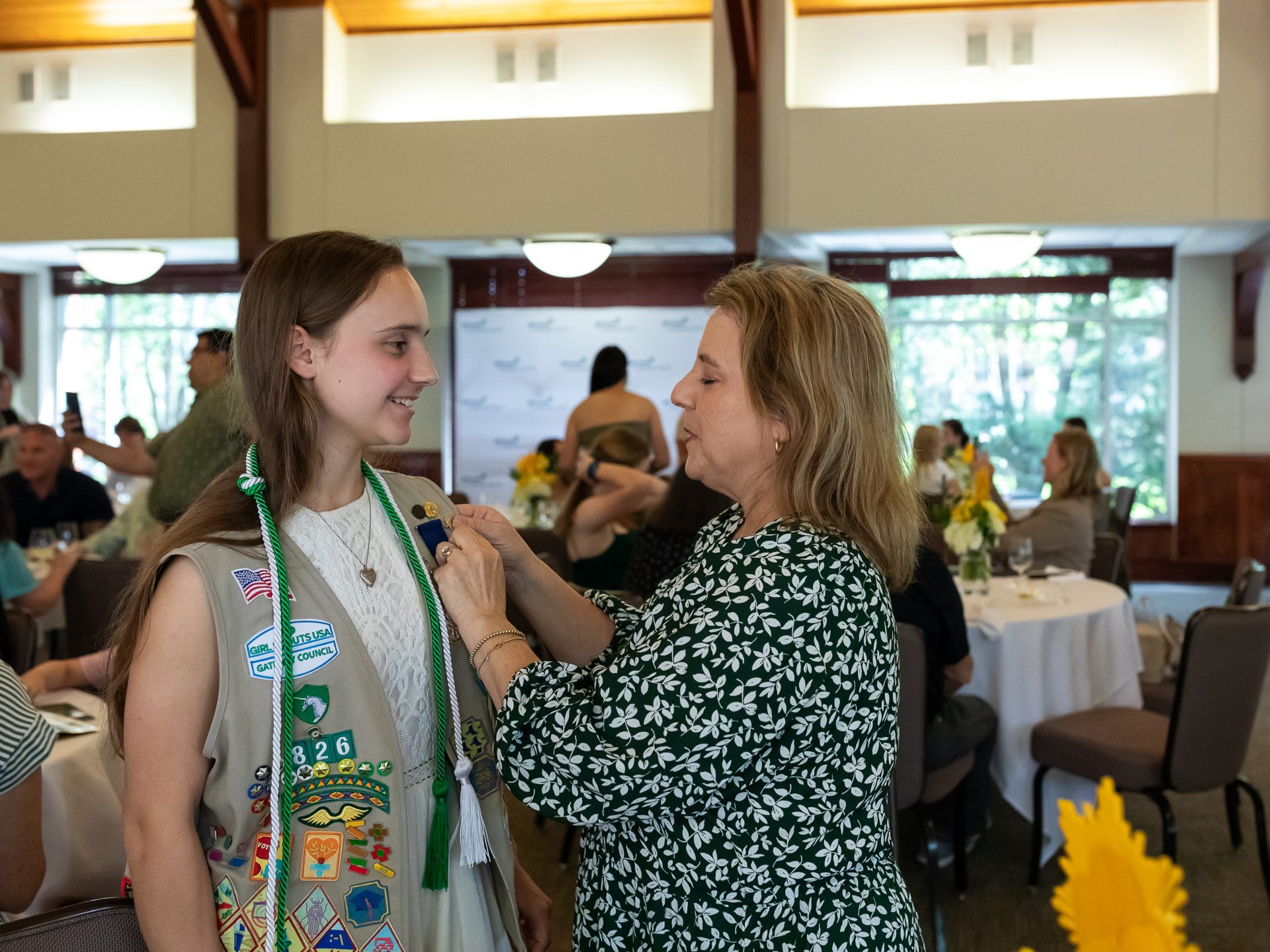 ambassador high school girl scout wearing sash outside against green background