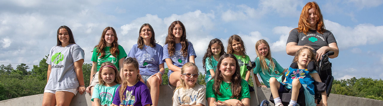  three young girl scouts with their arms wrapped around one another and smiling at the camera 